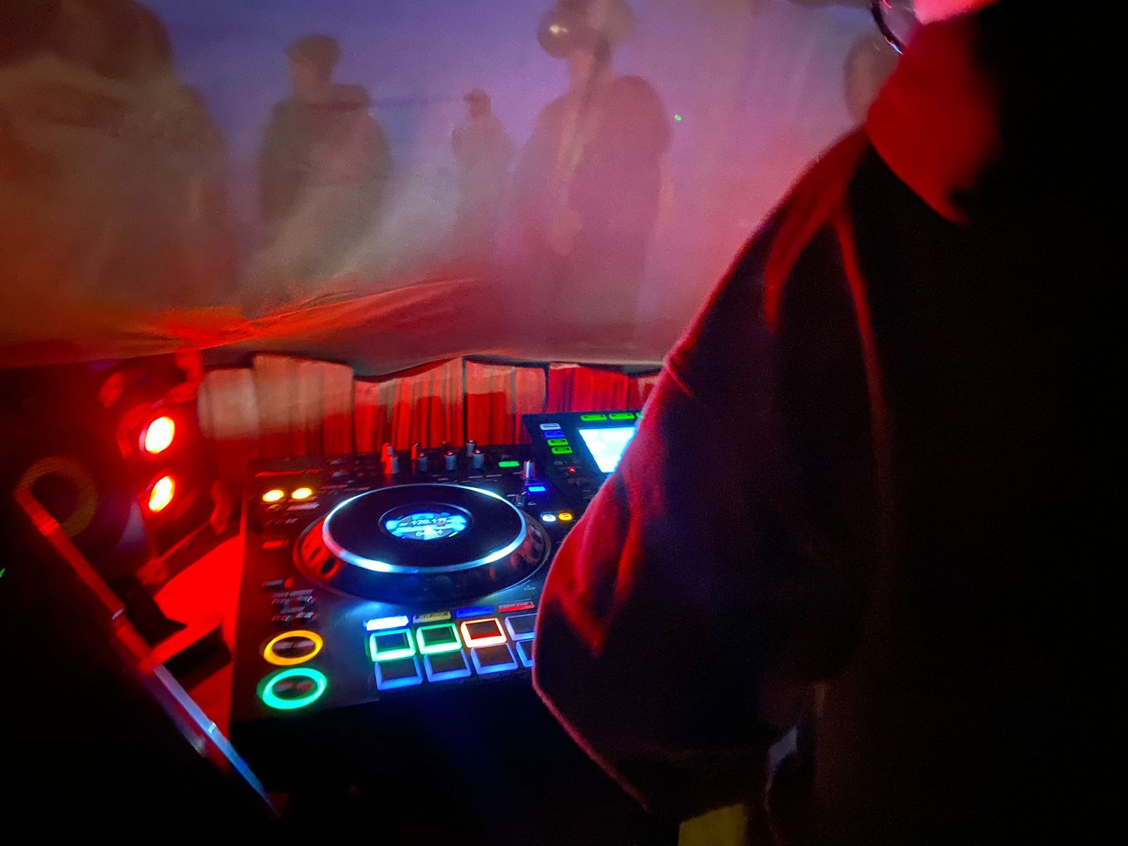 Pioneer CDJ glowing through red haze in a festival tent