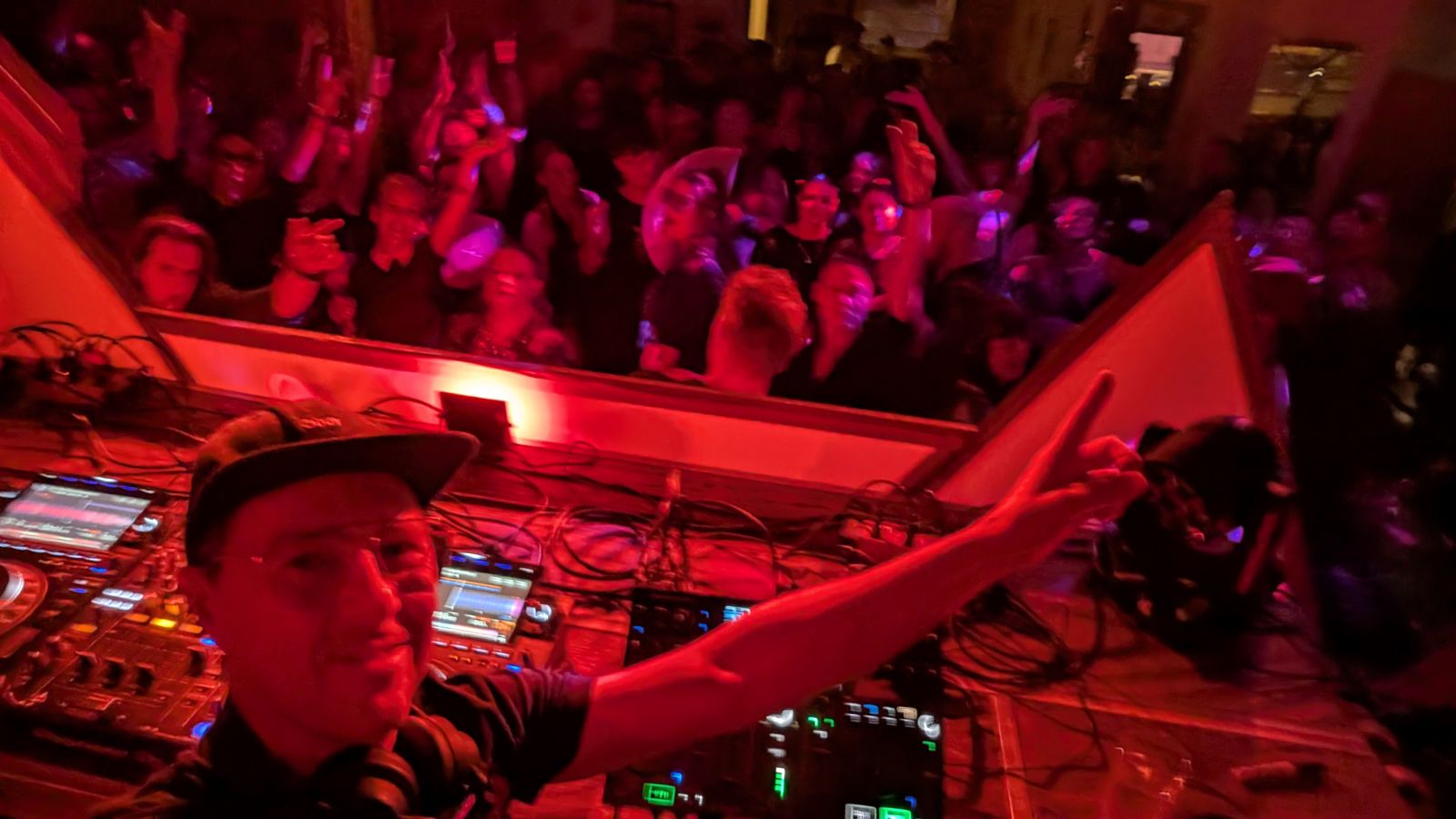 Packed crowd with hands up in front of the DJ booth at The Waverley Hotel